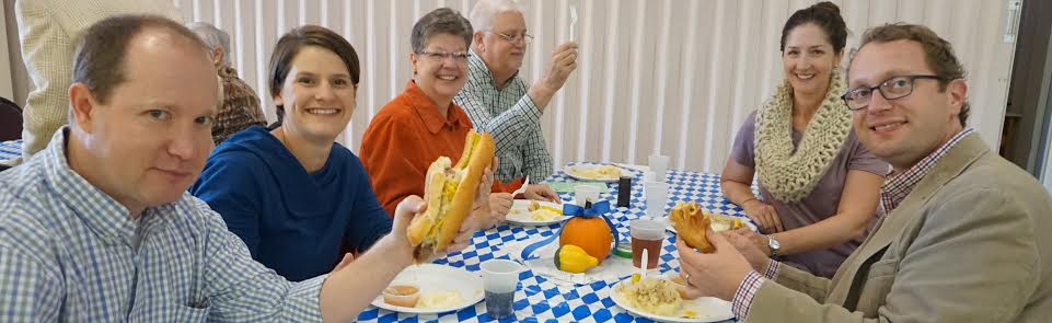 Two elderly people enjoying a meal together at a table with blue-checkered tablecloth.