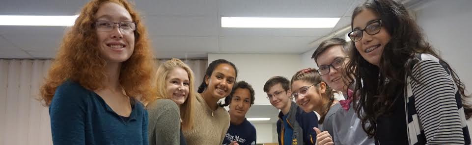 A group of five diverse young people smiling indoors.