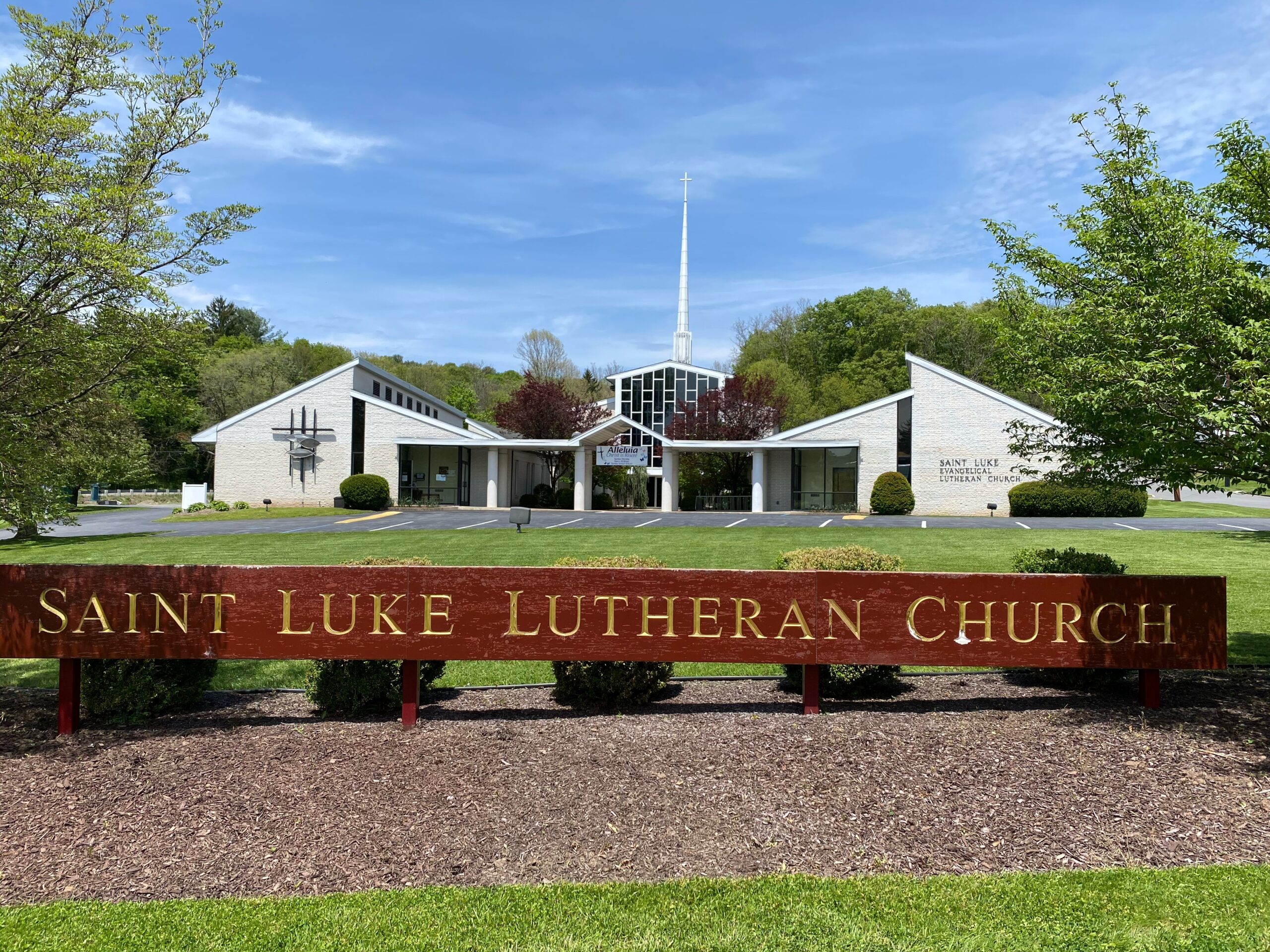 Saint Luke Lutheran Church sign with trees and a clear sky.