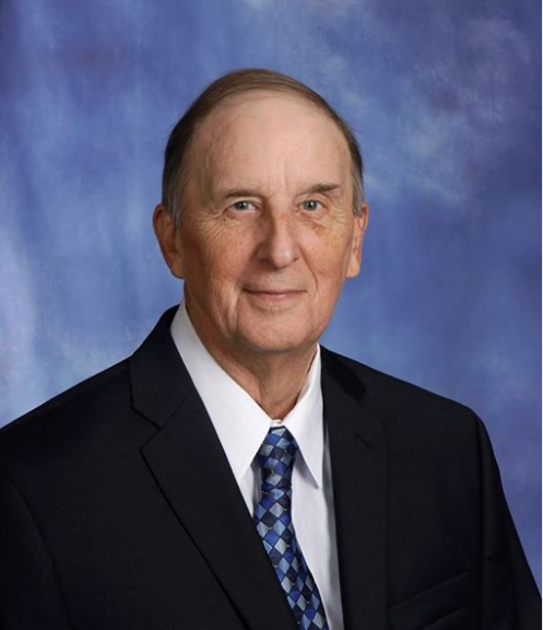Professional portrait of an elderly man in a suit and tie.