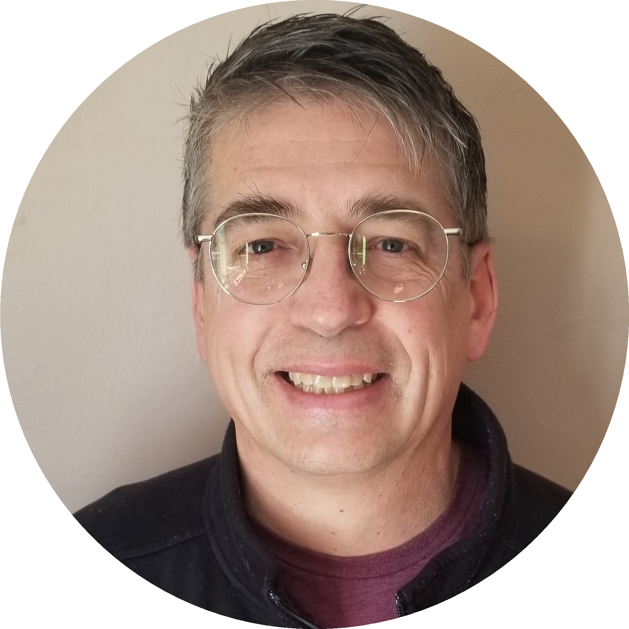 Smiling man with glasses and gray hair in a casual setting.