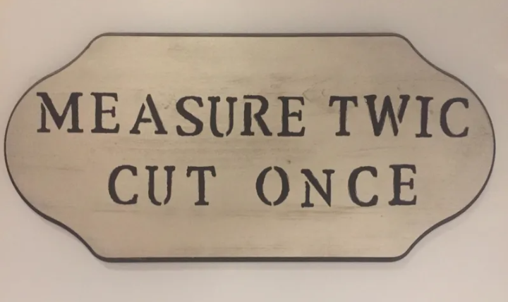 A vintage sign with the phrase 'MEASURE TWICE CUT ONCE.'