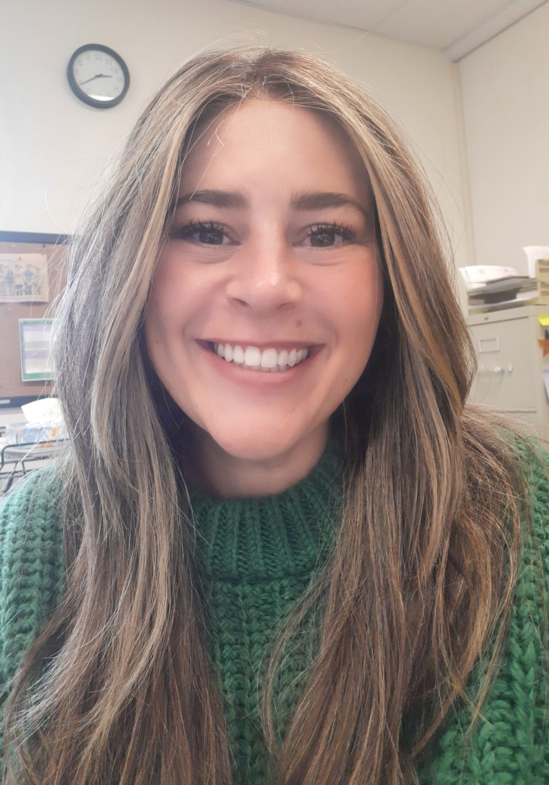Smiling woman in a green sweater indoors.