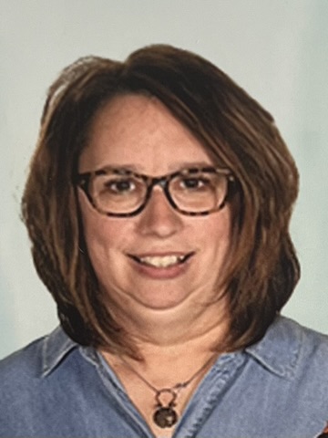 Smiling woman with glasses and shoulder-length brown hair.