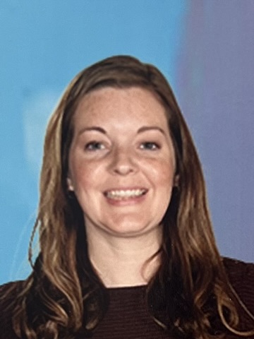 A smiling woman with long brown hair against a blue background.